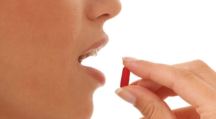 woman holding a pill up to her mouth