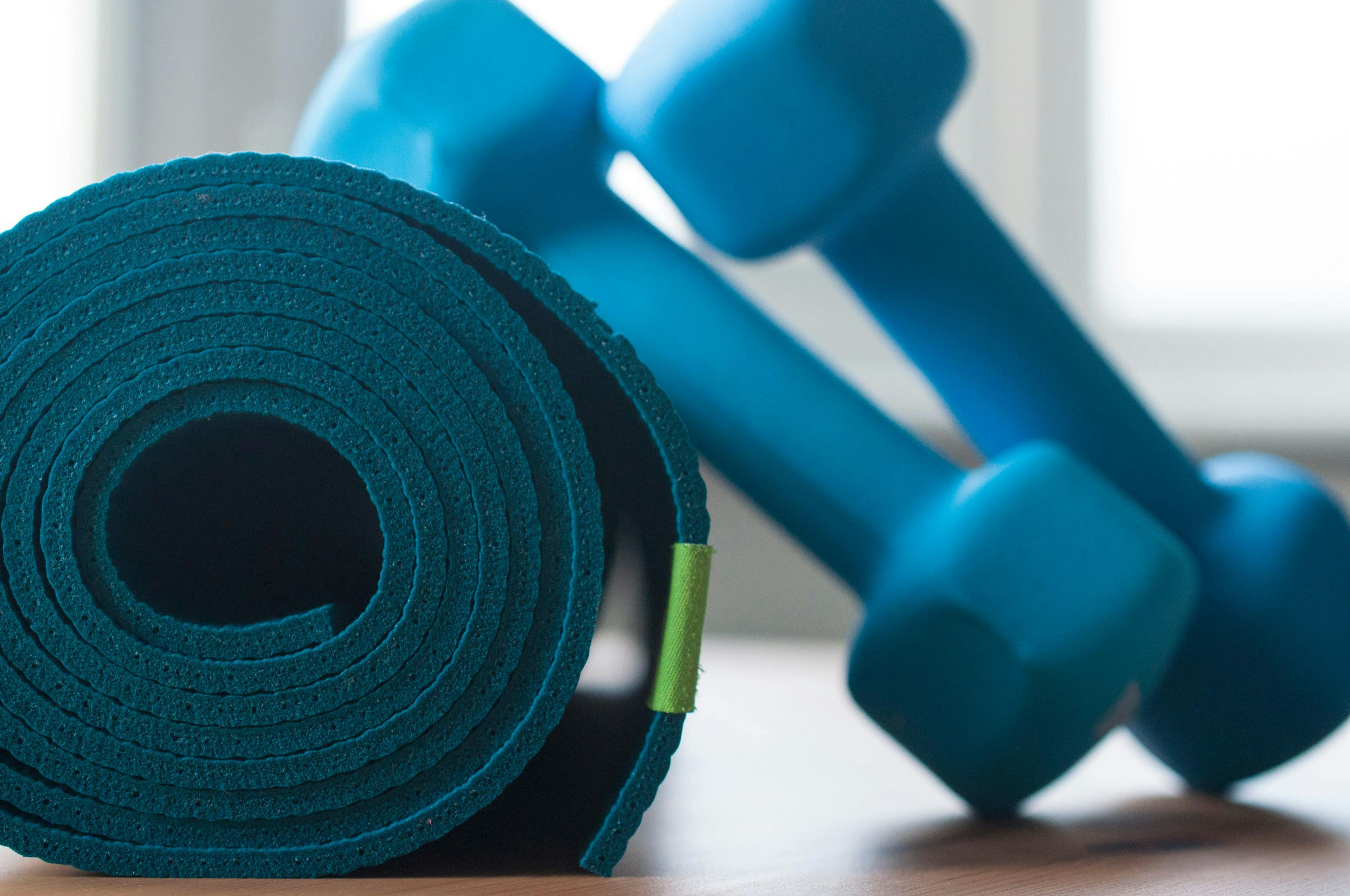 a blue rolled yoga mat and blue dumbbells 