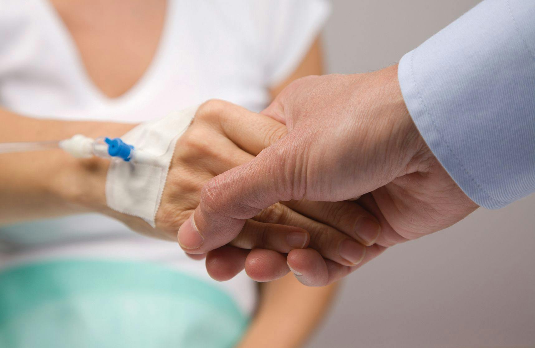 man holding hands with a woman who is hooked up to an IV