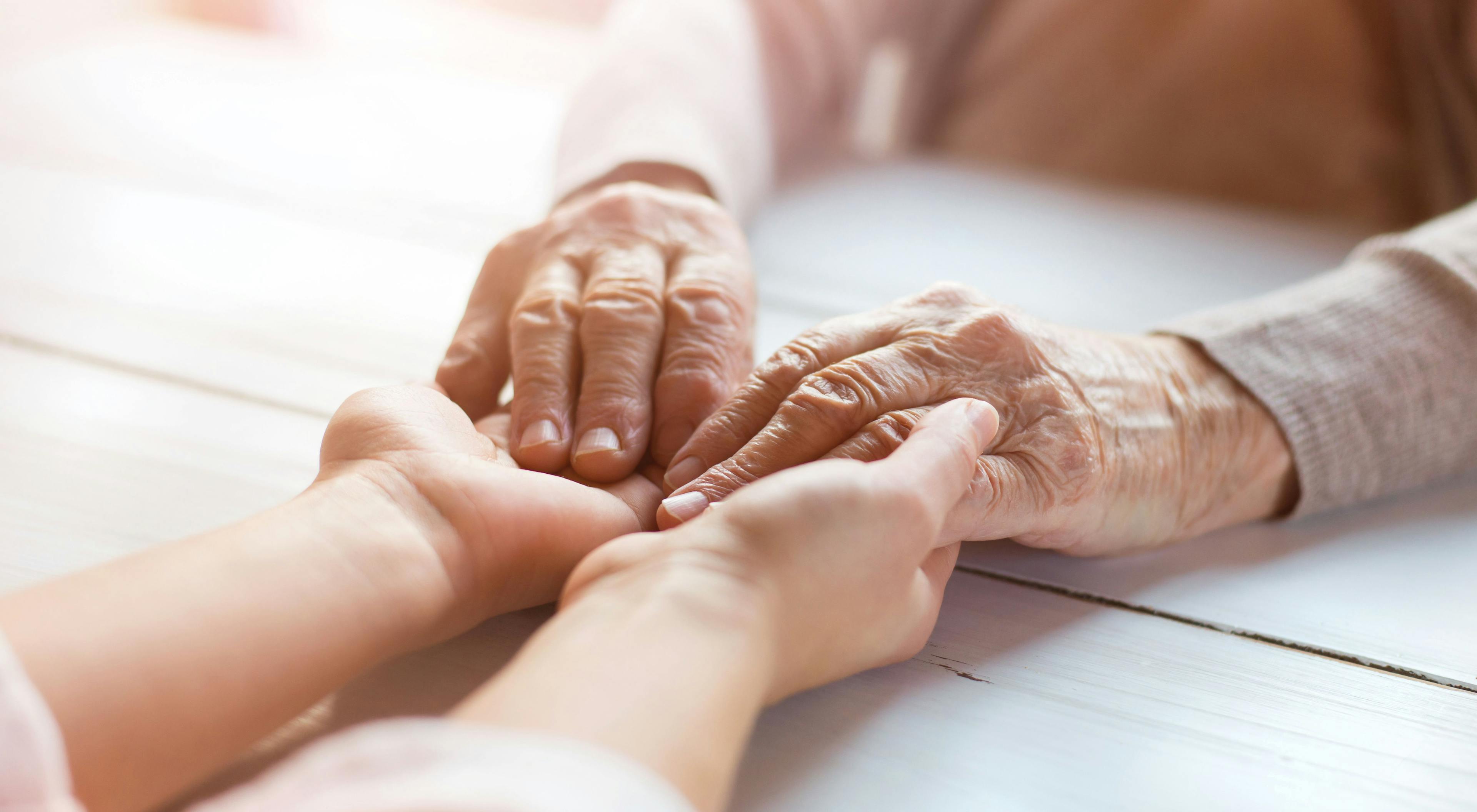Image of a caregiving holding the hands of a patient.