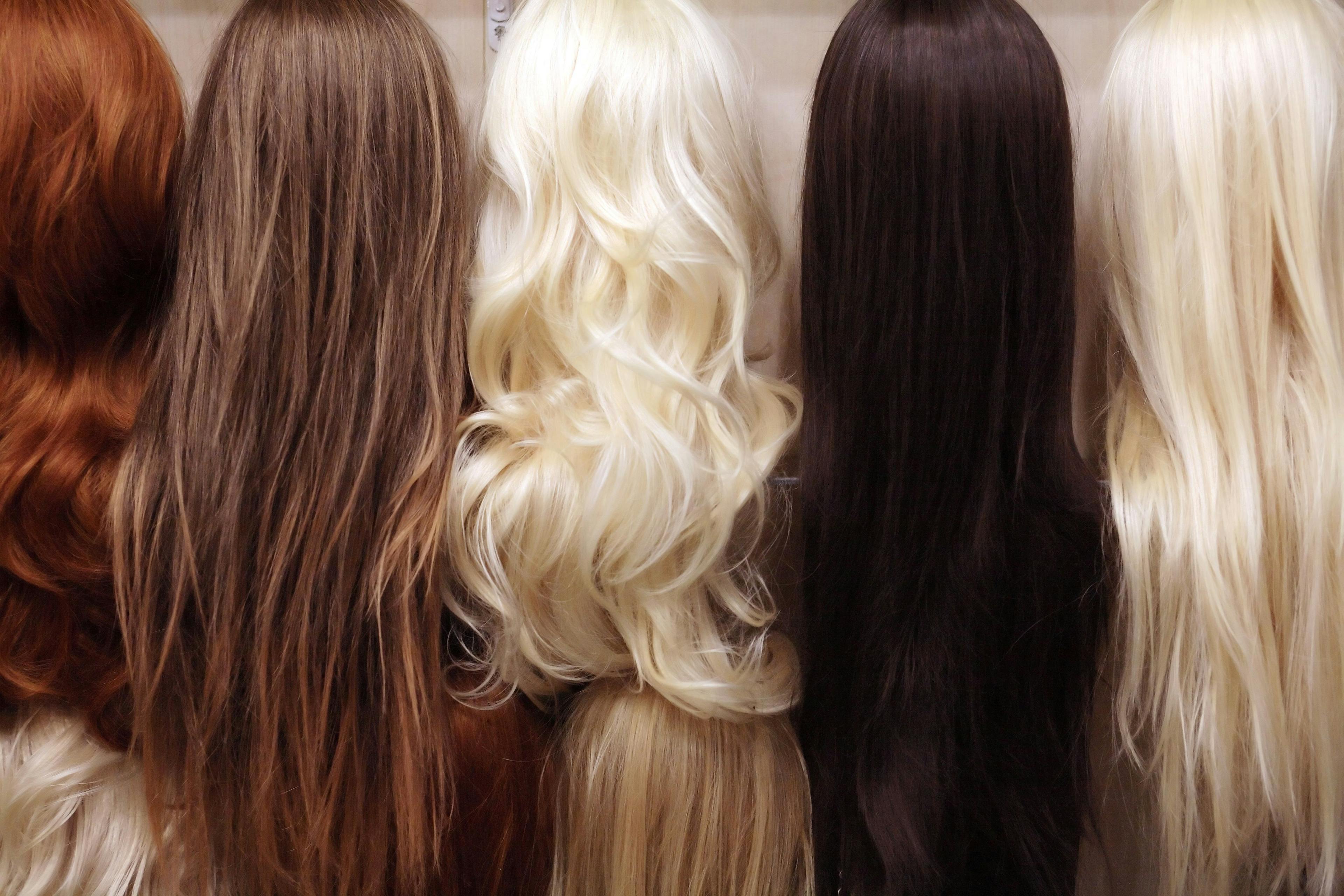 Image of eight different wigs of different colors: blonde, dark brown, red and light brown.